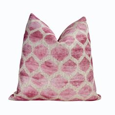 a pink and white pillow with an intricate pattern on the front, sitting against a white background