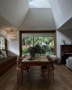 a dining room table and chairs in front of a large window with an open skylight