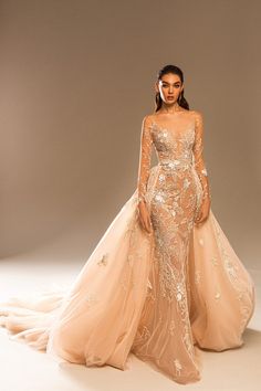 a woman in a long sleeved wedding dress with an open back and gold embellishment