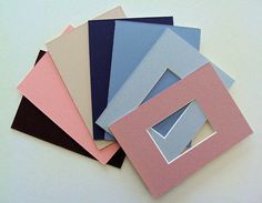 five different colored papers are stacked on top of each other, with one being cut into smaller shapes