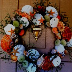 a wreath with seashells and starfish is hanging on the front door,