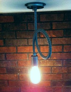 a light that is hanging from the ceiling next to a brick wall with a cord on it