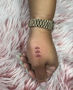 a woman's hand with the number forty four tattooed on her left wrist, in front of a fluffy pink background