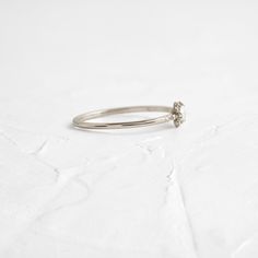 a white gold ring with a single diamond on the top, sitting on a plain surface