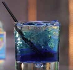 a blue liquid in a glass with a black straw