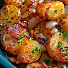 cooked potatoes and onions with herbs in a blue bowl on a table top, ready to be eaten