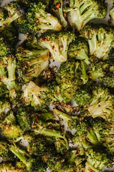 broccoli florets are arranged on a sheet of parchment paper with red pepper sprinkles