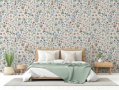 a bed with pillows and blankets in front of a wallpapered background that has flowers on it