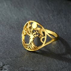 a gold ring sitting on top of a black stone surface with an intricate design in the middle