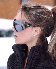 a woman with her hair in a pony tail wearing sunglasses and looking off into the distance