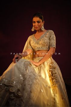 Illuminate your presence with our stunning Beige Designer Lehenga Choli from Palkhi Fashion. Crafted with precision and adorned with intricate embellishments, this ensemble exudes timeless grace and sophistication. The soft beige and gold hue enhances its versatility, making it perfect for a myriad of special occasions. Full flair lehenga choli is a testament to impeccable craftsmanship, weaving jacquard, petite sequin embroidery, handwork, mirror, and stoneborderwork work followed by refined st Reception Organza Sets With Pallu, Elegant Organza Lehenga With Intricate Embroidery, Festive Wedding Choli In Organza, Gold Embellished Wedding Sets, Transitional Raw Silk Sets For Reception, Embellished Sets For Wedding And Eid, Elegant Tissue Silk Lehenga With Zari Work, Elegant Lehenga With Zari Work On Tissue Silk, Wedding Sharara In Tissue Silk For Transitional Season