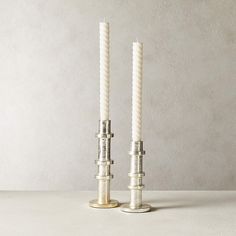 two white candles sitting next to each other on a table