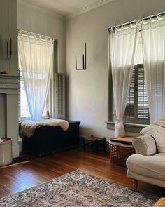 a living room filled with furniture and a fire place next to a window covered in sheer curtains