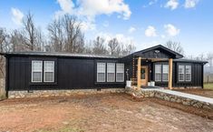 a black house sitting in the middle of a field