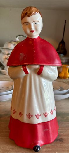 a ceramic figurine with a red cape on it's head sitting on a table