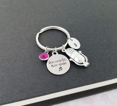 a silver keychain with a car and music notes on it, sitting on top of a book