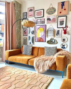 a living room filled with orange couches and pictures on the wall next to a window