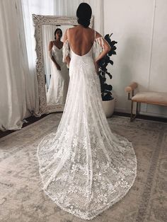 the back of a woman's wedding dress in front of a mirror