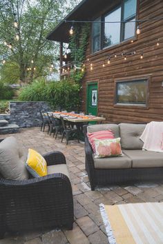 an outdoor seating area with patio furniture and string lights hanging from the side of a house