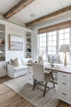 a home office with white furniture and wood beams