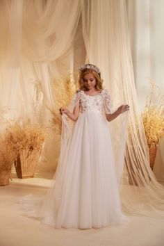 Elevate your little girl's special occasion with the stunning Pentelei Couture 3624 Communion Dress. This exquisite gown features a 3D floral attached cape in sheer fabric embellished with shimmering crystals and pearls, adding a touch of glamour to her look. The floral bodice creates a sweet and charming appeal, while the sheer floor length layered tulle skirt adds a soft and ethereal touch. Perfect for a flower girl or communion ceremony, this dress is sure to make your little princess feel li Confirmation Dresses, Girls Communion Dresses, Lace Cape, Layered Tulle Skirt, Girls Pageant Dresses, Christening Dress, Couture Dress, Communion Dresses, Christening Gowns