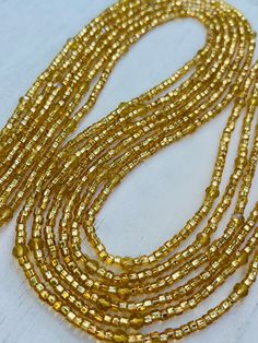 Description One 50 inch tie-on luxury waist bead Created on a durable Ghanian string Shimmery gold seed beads with faceted gold crystals Adjustable Gold Necklace With Polished Beads, Adjustable Gold Waist Chain For Gift, Gold Rondelle Bohemian Jewelry, Yellow Gold Beaded Necklaces With Colorful Beads, Gold Bohemian Waist Chain With Colorful Beads, Elegant Multi-strand Gold Beads, Bohemian Gold Rondelle Jewelry, Bohemian Gold Waist Chain With Colorful Beads, Adjustable Gold Waist Chain With Colorful Beads