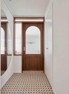 an empty room with a door and mirror on the wall, next to a tiled floor