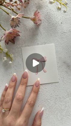 a woman's hand holding onto a piece of paper with flowers in the background