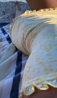 a close up of a person laying on a towel near the ocean with their feet in the sand