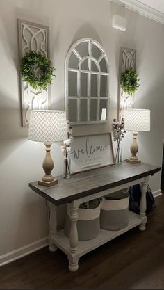 a table with two lamps on top of it next to a mirror and lamp shade