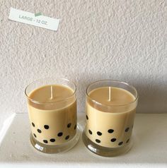 two candles sitting on top of a counter next to each other with black dots painted on them