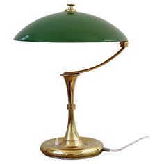 a green table lamp with a white cord attached to it's end and a gold base