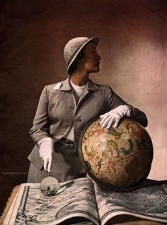 a woman in white gloves is holding an open book with a globe on top of it