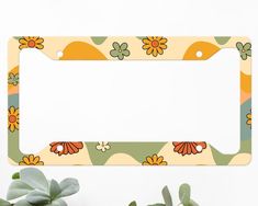 an orange and green flowered license plate holder with succulents next to it