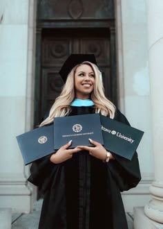 a woman in graduation gown holding two diplomas