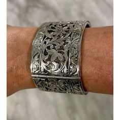 Silver wide pierced bracelet with floral motif. Safety chain and clasp enclosure. Likely silver plate. Signed on clasp. Antique Silver Bracelets For Formal Occasions, Formal Silver Cuff Bracelet With Sterling Clasp, Elegant Oxidized Finish Cuff Bracelet For Formal Occasions, Antique Silver Elegant Bangle, Formal Silver Cuff Bracelet With Box Clasp, Elegant Antique Silver Cuff Bracelet With Oxidized Finish, Elegant Silver Cuff Bracelet With Box Clasp, Elegant Silver Hinged Cuff Bracelet, Adjustable Silver Vintage Cuff Bracelet