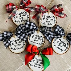 four decorated cookies with ribbons on top of a cloth tablecloth covered in plaid ribbon