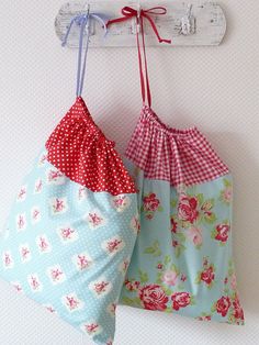 two bags hanging from a hook on a wall next to another bag with polka dots and flowers