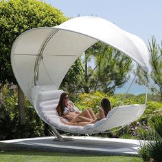 two women lounging in an outdoor lounge chair with canopy over the back and side