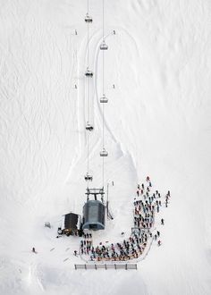 a group of people standing on top of a snow covered slope next to a ski lift