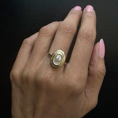 a woman's hand wearing a gold ring with a diamond in the center and on her finger