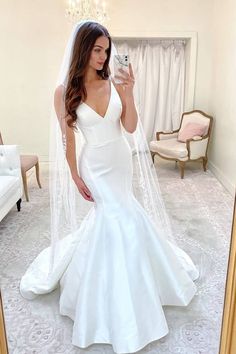 a woman taking a selfie in a mirror wearing a white wedding dress and veil