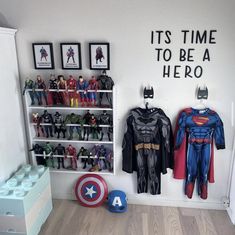 a room filled with toys and pictures on the wall next to a shelf full of batman costumes