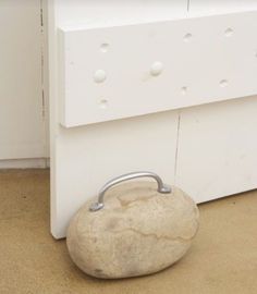 a rock sitting in front of a white door with a metal handle on it's side