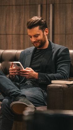 a man sitting in a chair looking at his cell phone