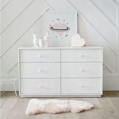 a white dresser in a room with an art print on the wall and sheepskin rug