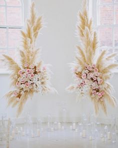 two vases filled with flowers and feathers on top of a table