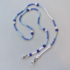 "Keep your mask close with this beaded mask leash that doubles as a cute glasses / sunglasses chain for your continued use post-pandemic.  This is an investment piece that's designed and crafted with high quality craftmanship to stand up to daily use. It only looks delicate!  - Dark blue and light blue iridescent & translucent beads separated with opaque white - Asymmetrical design - Japanese and Czech glass beads - Sterling silver hardware - Double strung on the strongest and most flexible beading thread available for exceptional durability and drape. 24\" length.   Production time is approx 3 days plus shipping. Rush production and rush shipping available as a shipping upgrade at checkout. Stay safe! <3" Adjustable Blue Glasses Chains With Colorful Beads, Blue Glasses Chains With Colorful Beads For Gift, Blue Glass Glasses Chains With Colorful Beads, Blue Glasses Chains With Colorful Beads As Gift, Blue Glasses Chain With Colorful Beads For Gift, Blue Glasses Chain With Colorful Beads As Gift, Blue Adjustable Chain Glasses Chains For Summer, Blue Adjustable Glasses Chain For Summer, Summer Blue Glasses Chain With Adjustable Feature