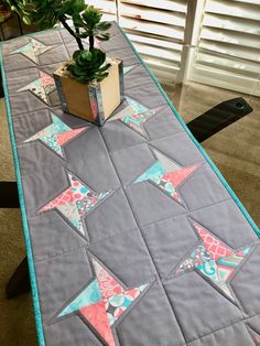 a table with a potted plant on top of it and a quilted runner