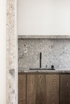 a kitchen sink sitting under a window next to a wooden cabinet and counter top with a faucet